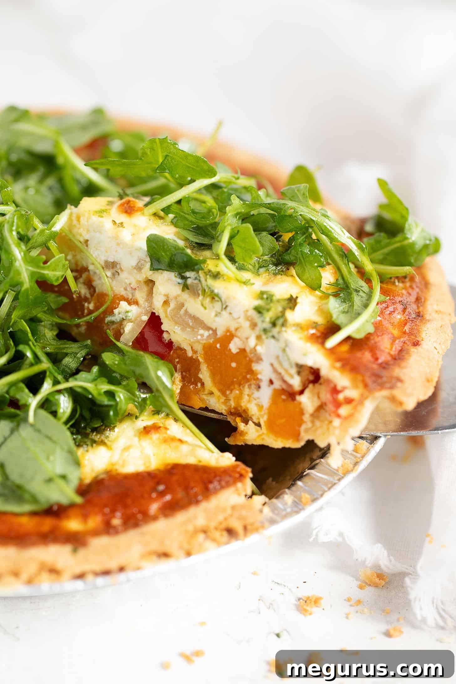 A close-up shot of a sliced butternut squash quiche, highlighting the rich texture of the filling and golden crust.