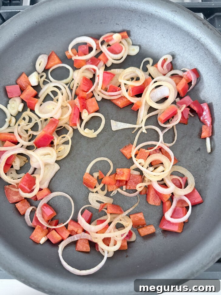Shallots and bell pepper cooking in a skillet until softened.