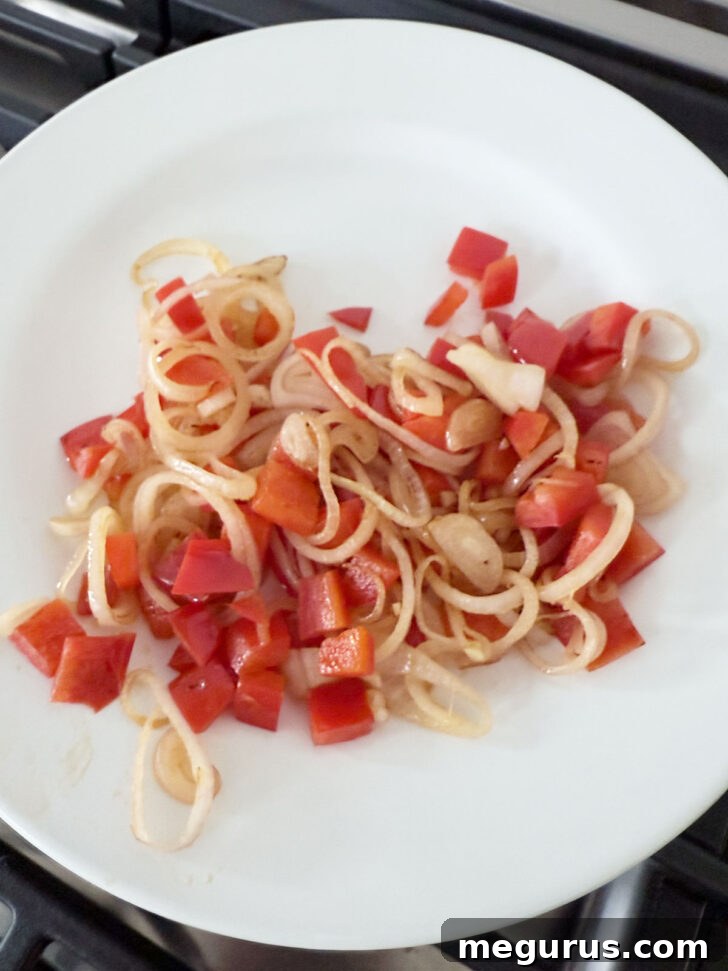 Cooked shallots and bell pepper removed to a plate.