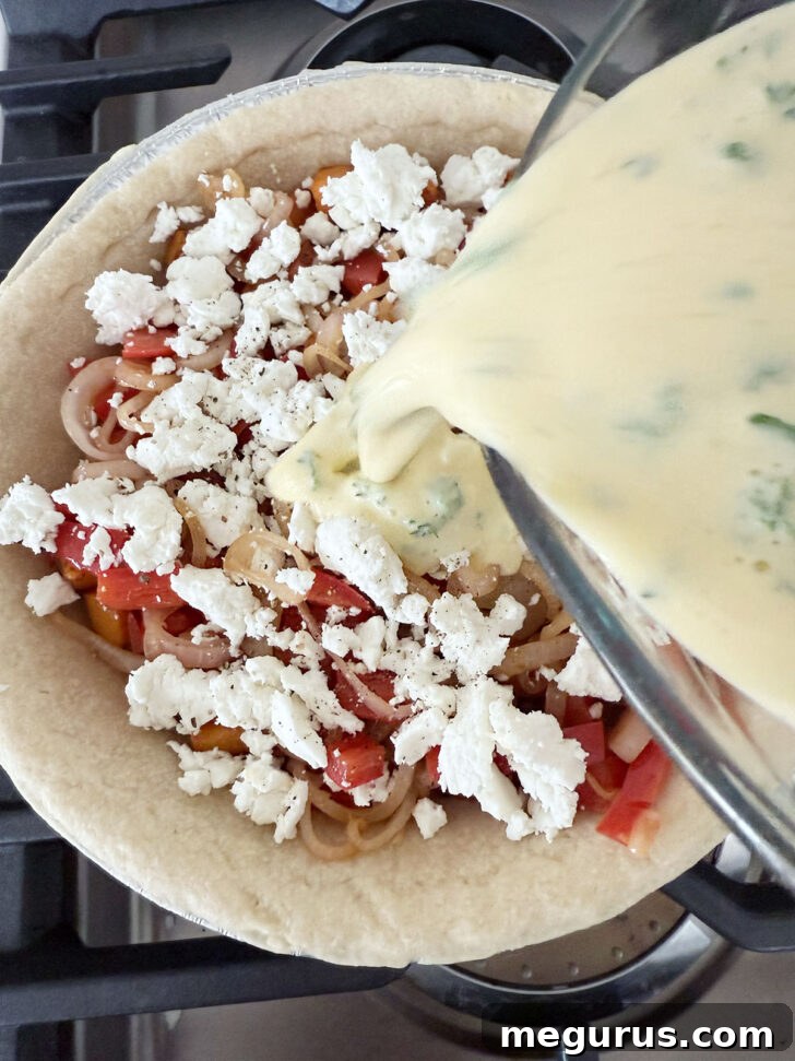 Pouring the egg mixture into the pie shell with vegetables and cheese.