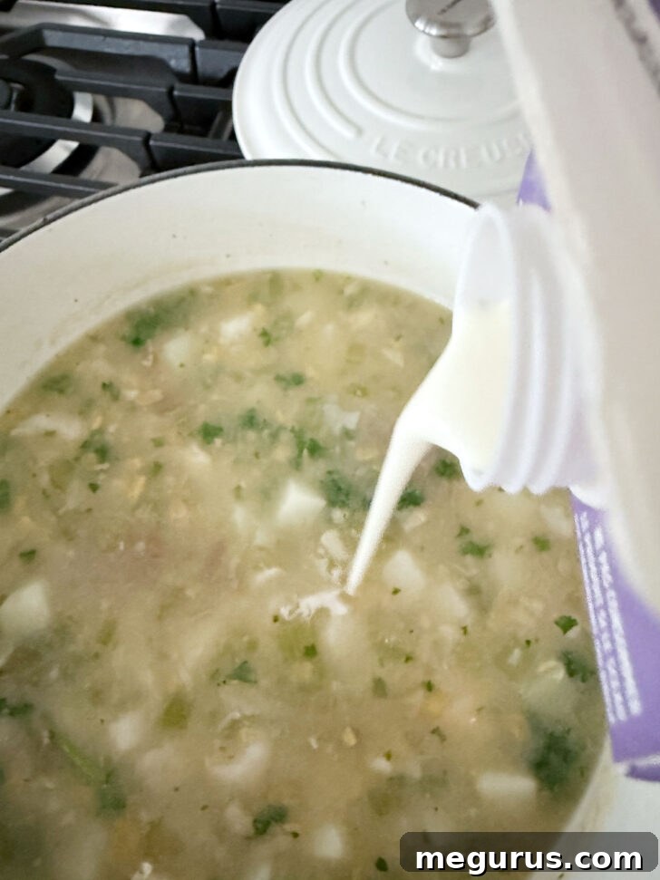 Drizzling a touch of heavy cream into the rich cod chowder.