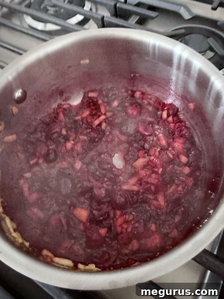 Cranberry apple glaze after cooking, showing softened fruits.