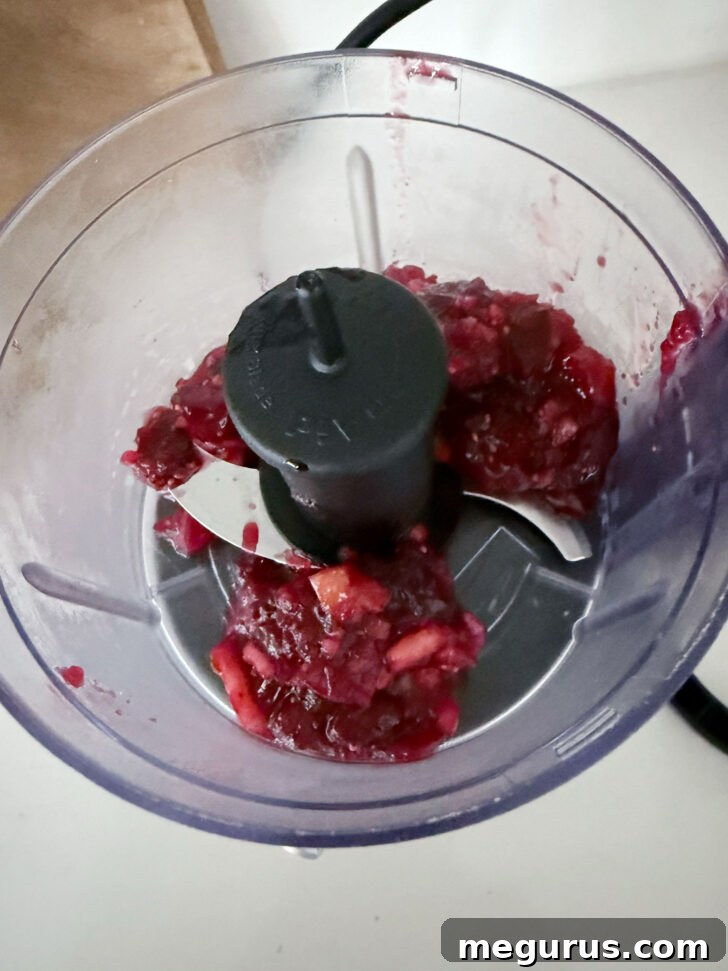 Processing the remaining cranberry apple mixture into a smooth glaze in a food processor.