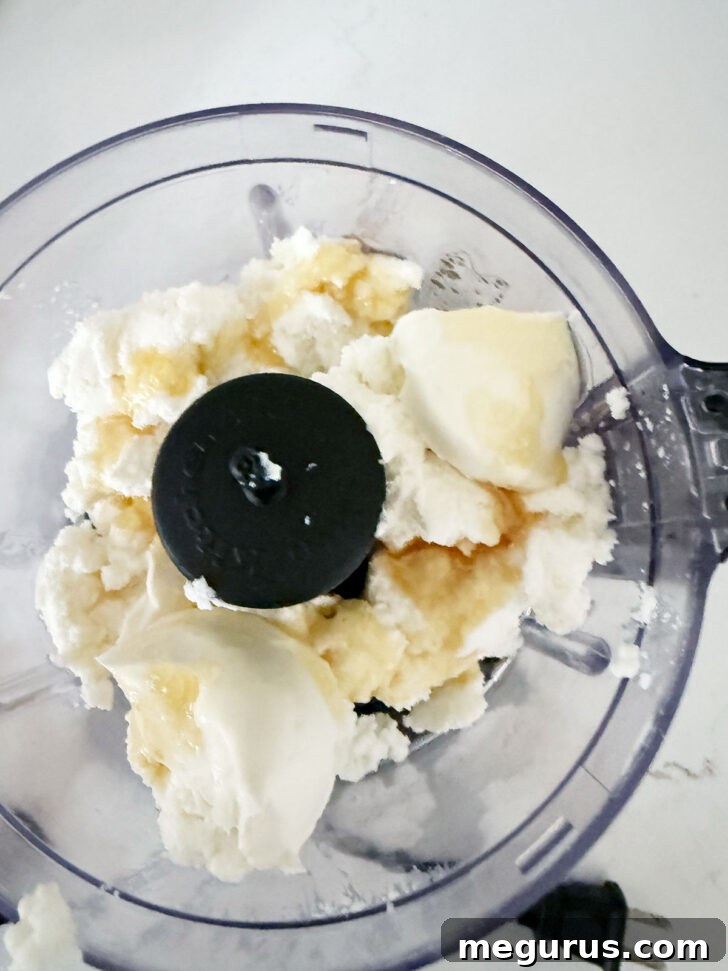 Whipped ricotta ingredients in a small food processor, including ricotta, cream cheese, honey, salt, and thyme.