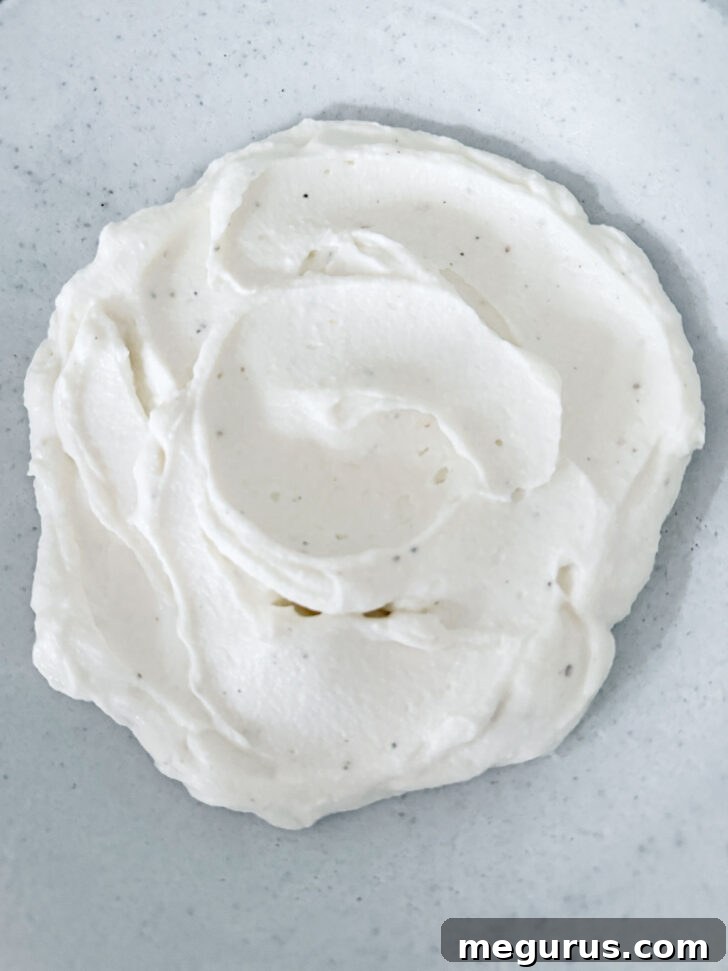 Whipped ricotta spread evenly into a shallow serving bowl, forming a smooth base for toppings.