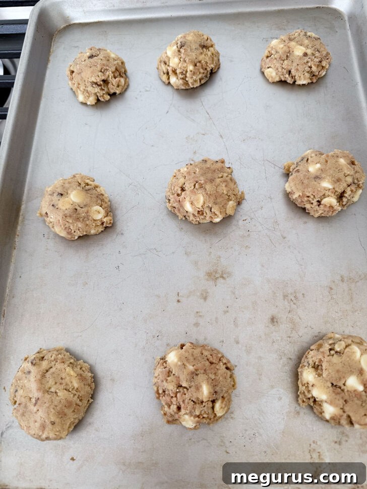 Cookie dough balls gently flattened with the palm of a hand on the baking sheet.