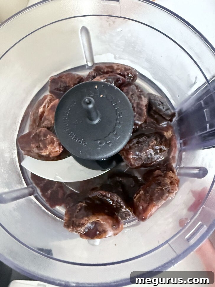 Pitted whole dates being placed into a food processor for preparation.