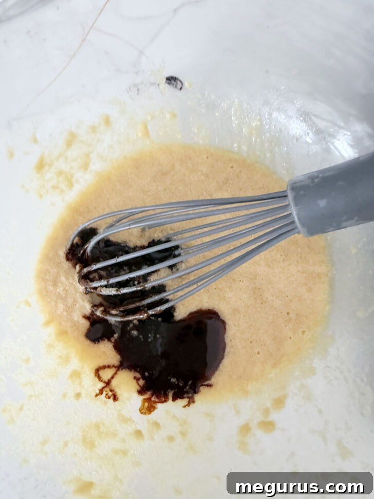 Vanilla extract being drizzled into the pudding batter, adding a layer of flavor.
