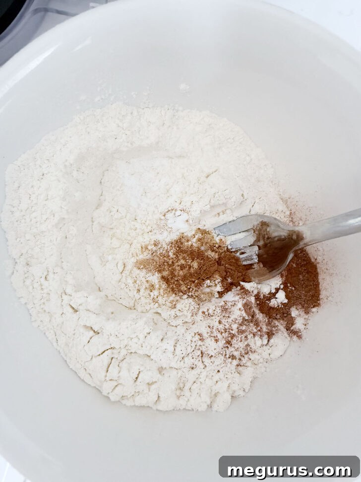 Various dry ingredients, including flour and spices, are whisked together in a small bowl.