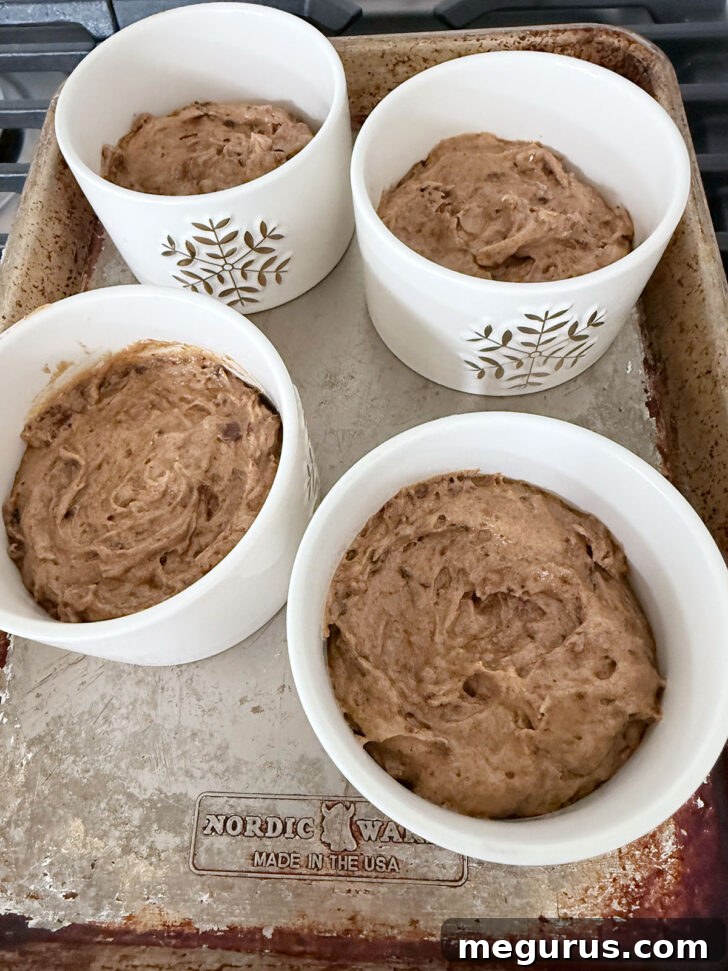 Pudding batter evenly divided between four greased ramekins, ready for baking.