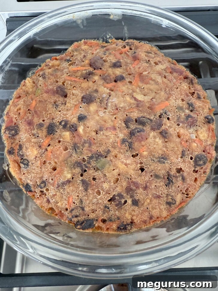 Cooked Christmas pudding in a bowl after steaming, looking rich and golden.