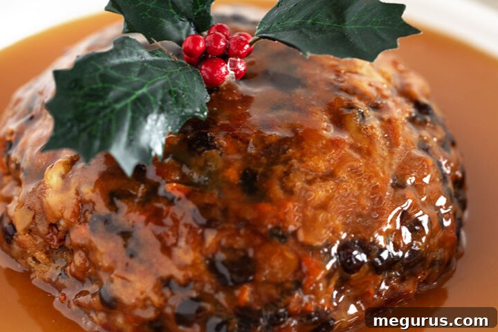 Christmas pudding with rum sauce on a serving plate, ready to be enjoyed.