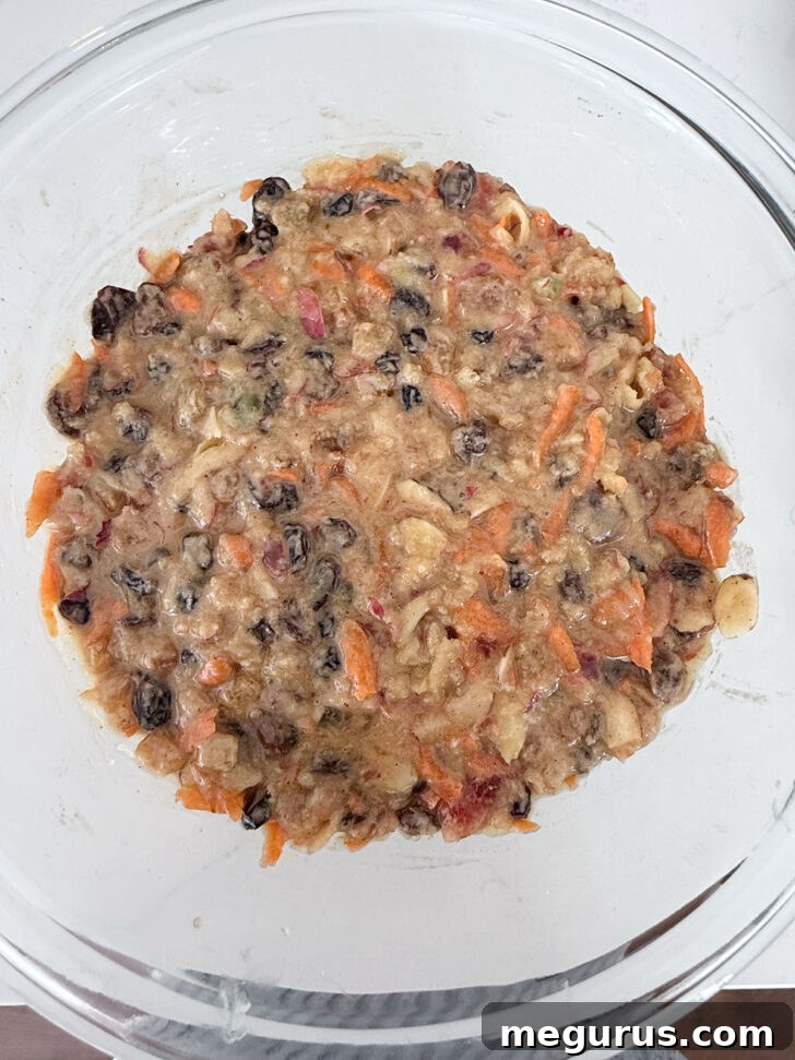 Christmas pudding batter being spooned into a greased glass steaming bowl.