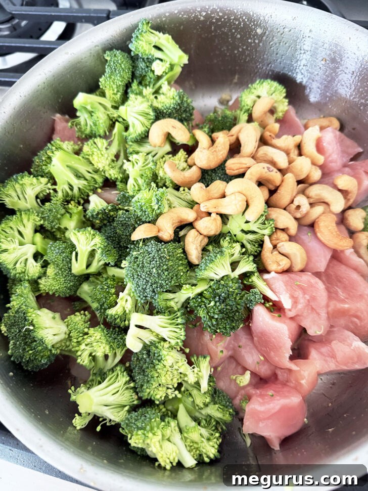 Broccoli, chicken and cashews added to a hot skillet.