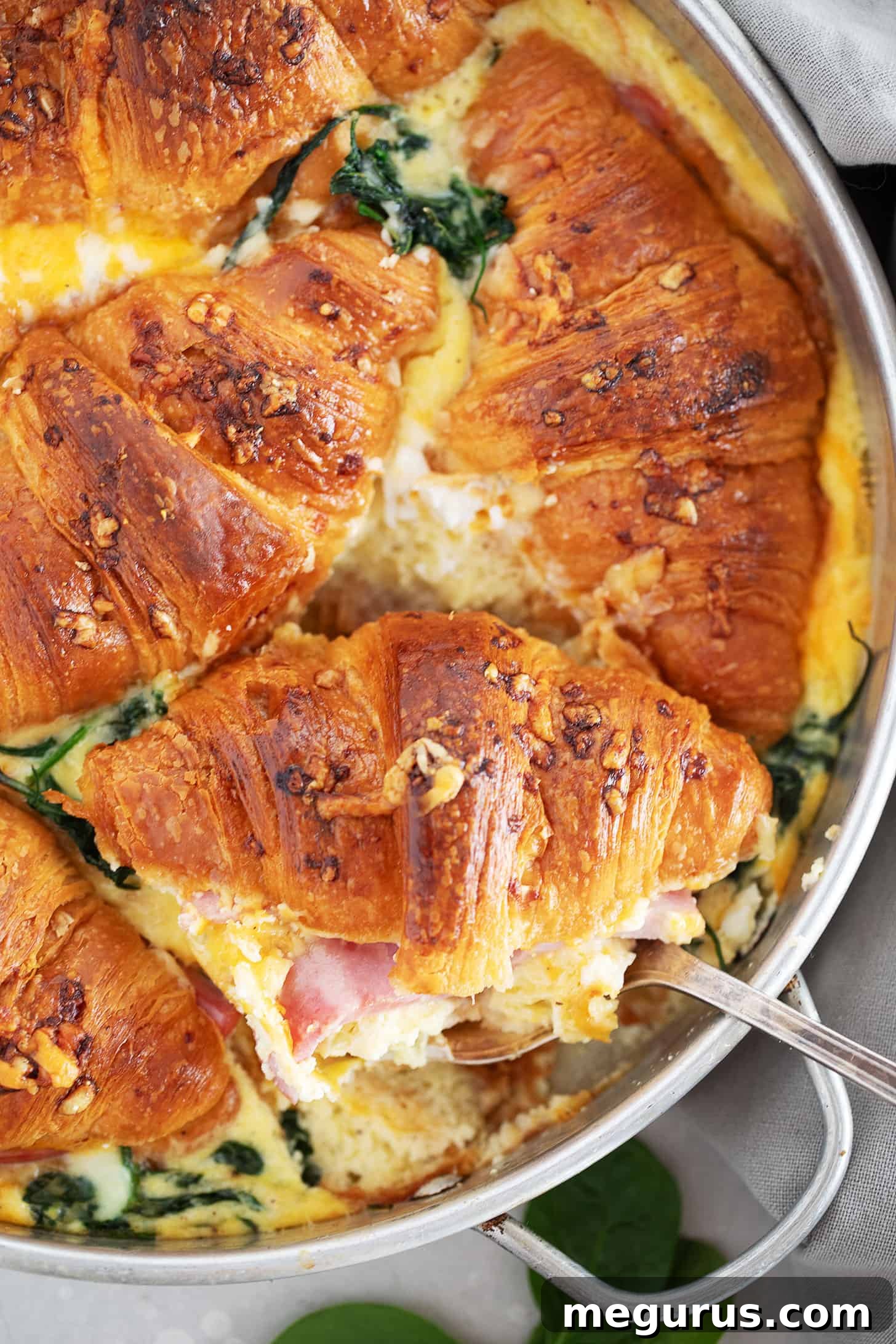Baked ham and cheese croissant bake in a round baking pan, with a golden-brown crust.
