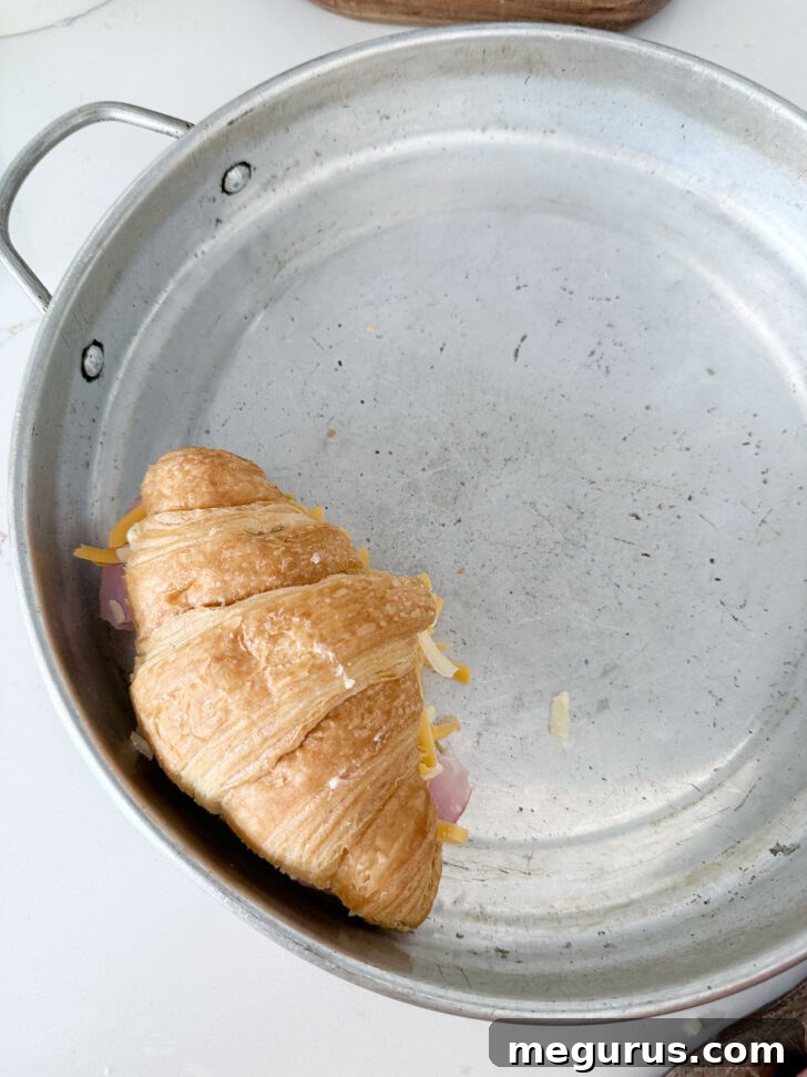 Placing a filled croissant into a round baking pan.