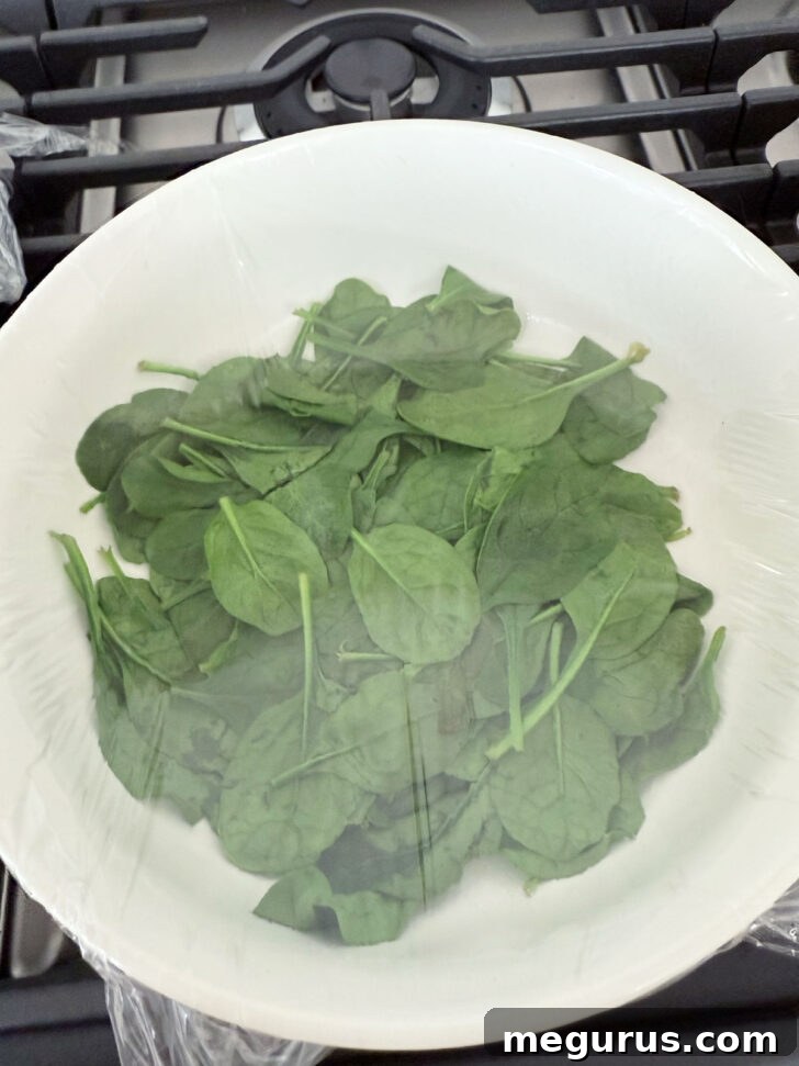 Fresh spinach wilting in a bowl.