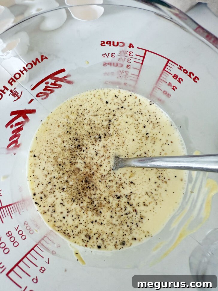 Egg custard mixture in a clear measuring cup.