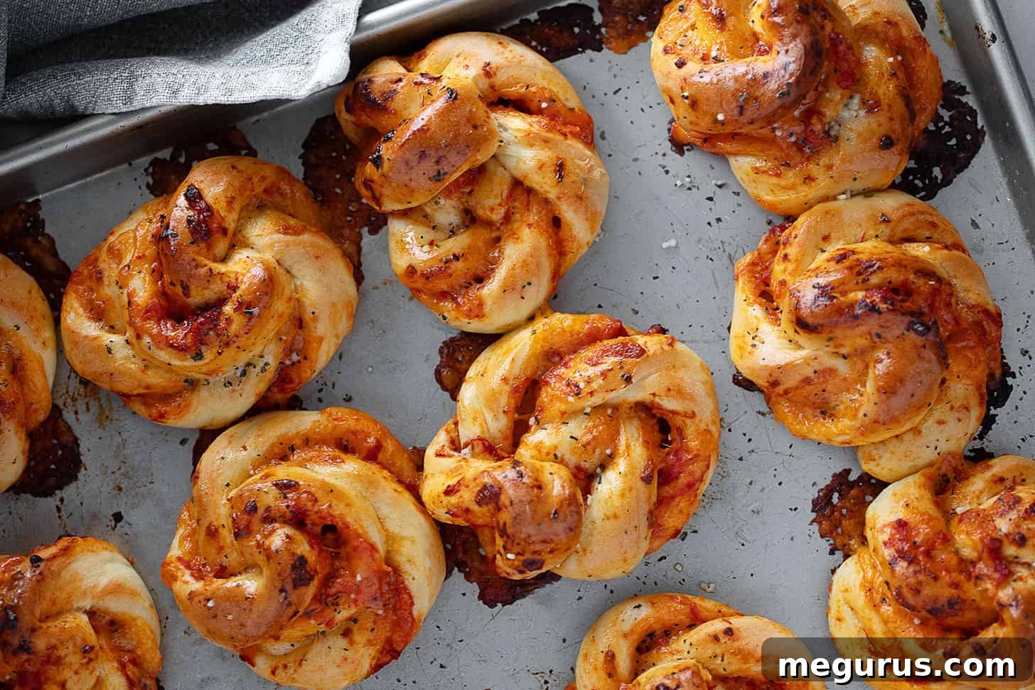 Golden brown pizza twists fresh from the oven, arranged on a baking sheet, glistening with garlic butter.