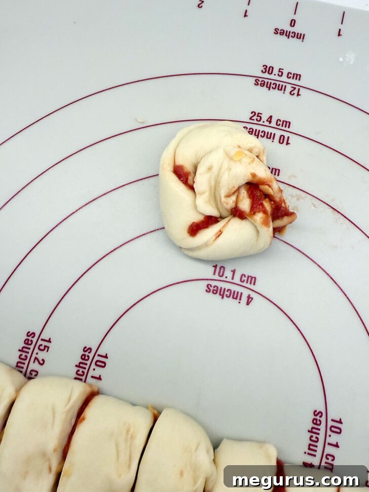 A twisted dough strip being coiled into a knot or spiral on a work surface.