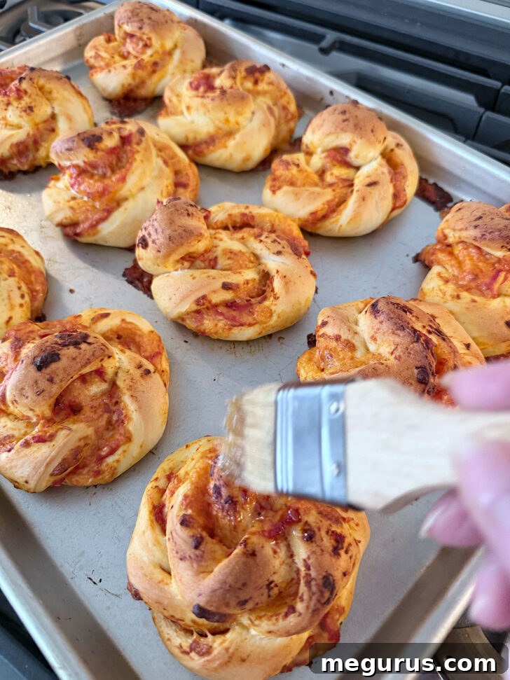 Baked pizza twists being brushed with garlic butter fresh out of the oven.