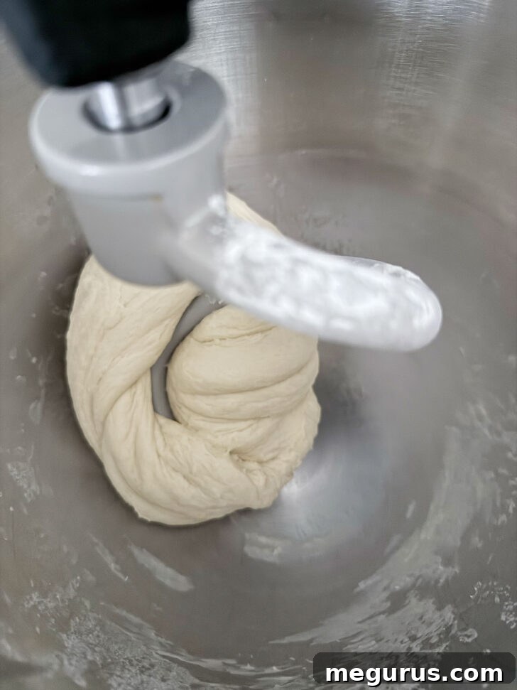 Smooth, elastic dough resting in a stand mixer bowl after kneading.
