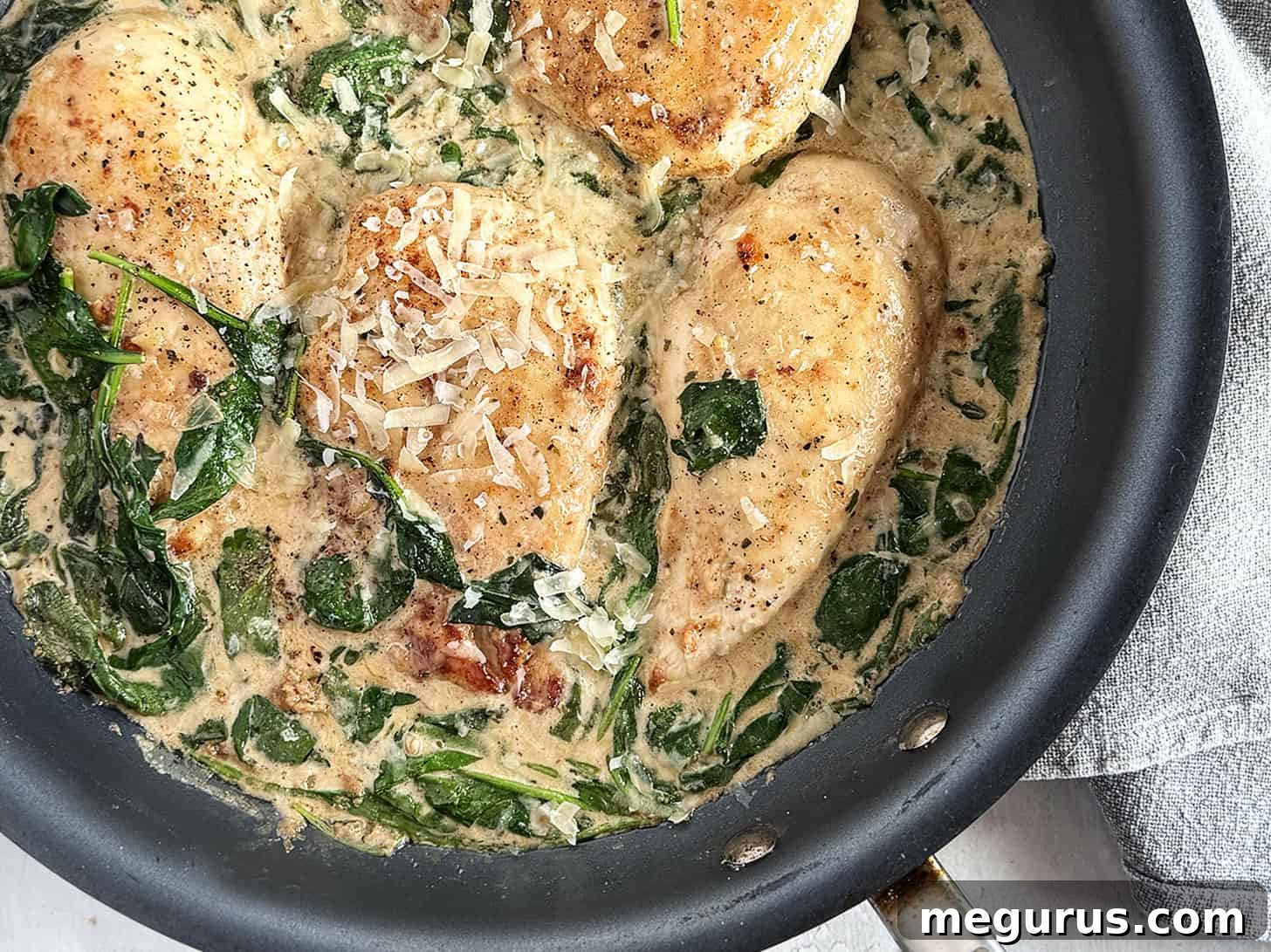 A close-up of beautifully cooked Chicken Florentine in a skillet, showcasing golden-brown chicken cutlets bathed in a creamy spinach sauce, ready to be served.