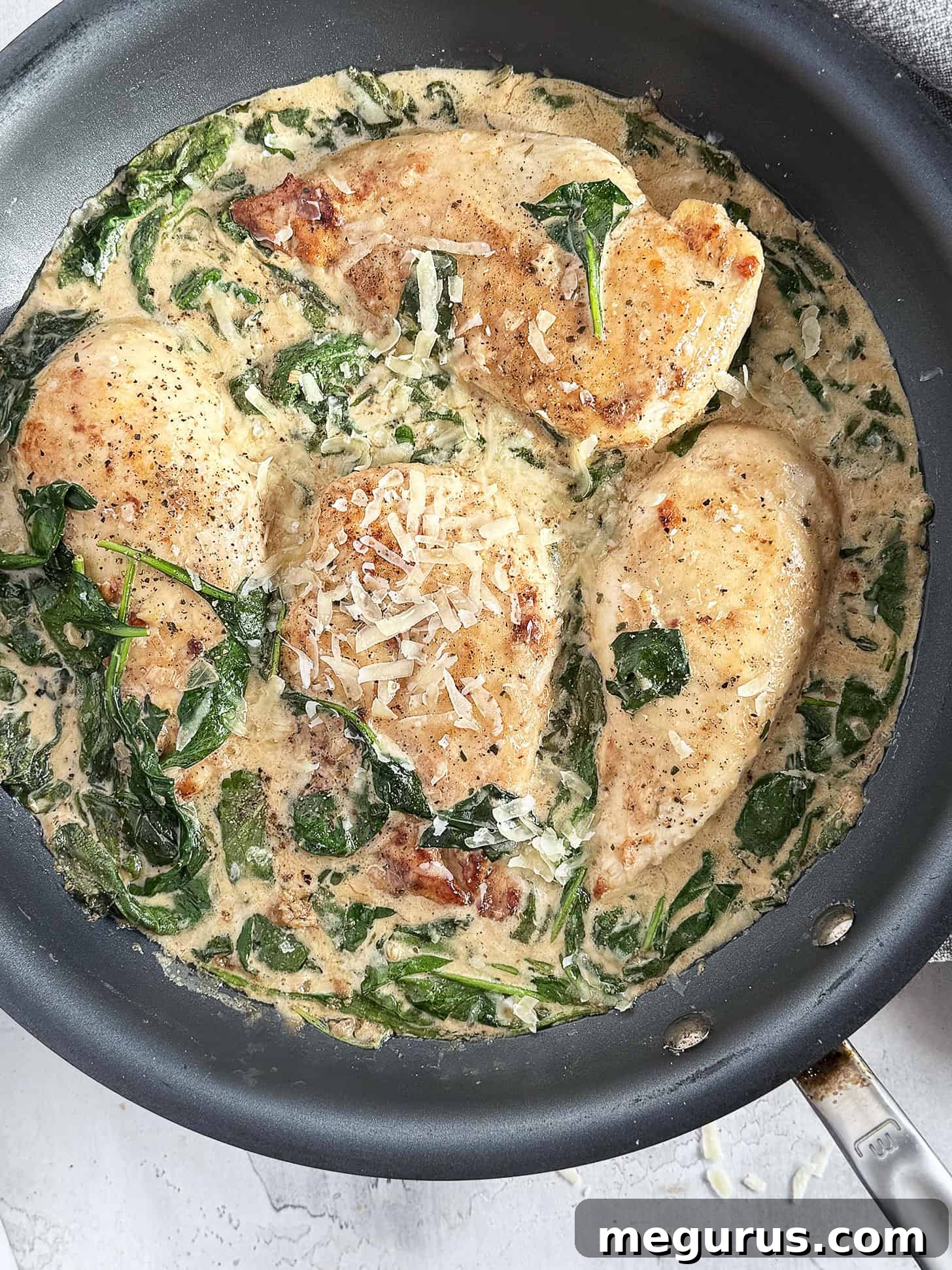 A large skillet filled with Chicken Florentine, garnished with fresh herbs and extra Parmesan, ready to be served family-style.