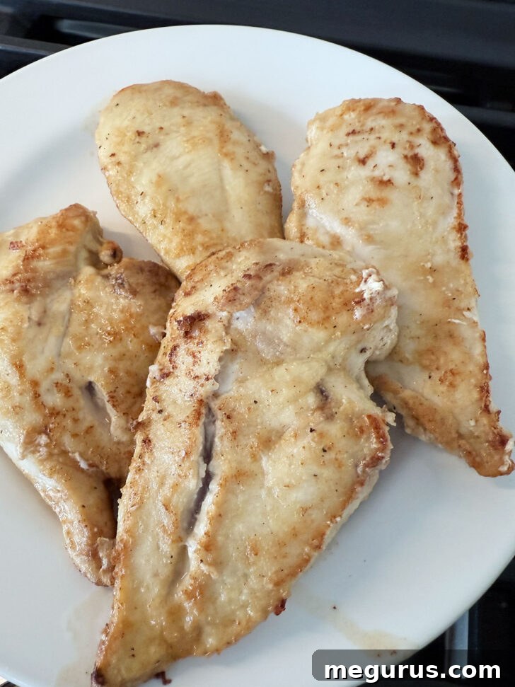 Browned chicken cutlets removed from the skillet and resting on a plate.