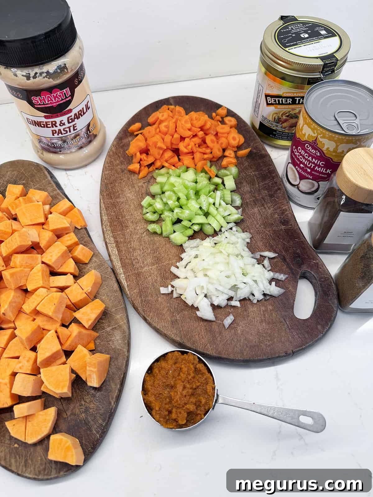 Fresh ingredients for sweet potato coconut curry soup, laid out on a wooden surface.