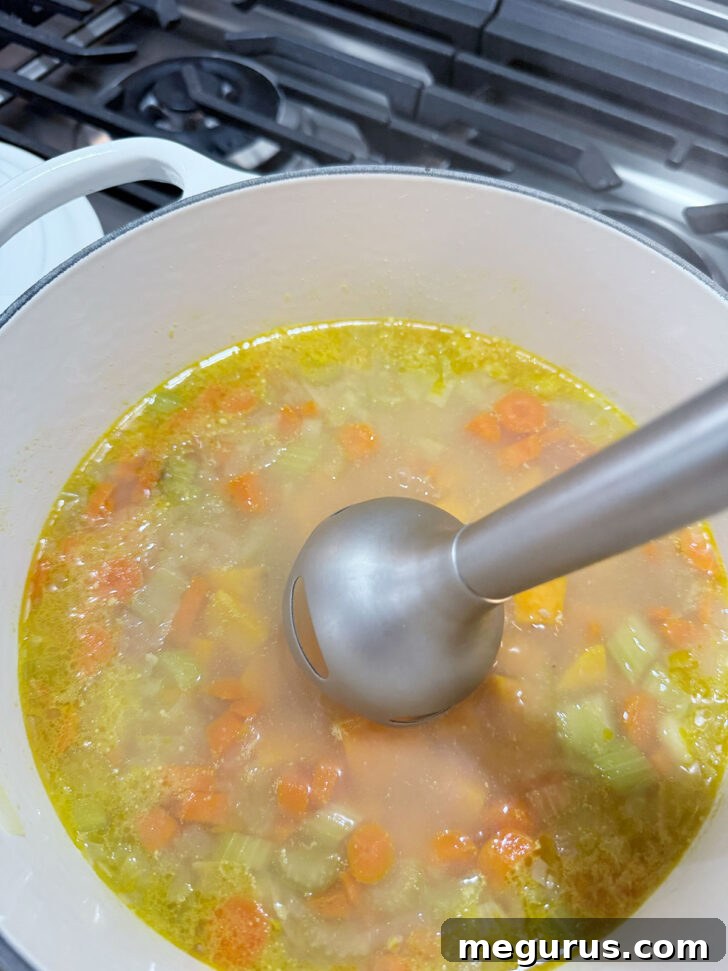 Using and immersion blender to puree the soup.