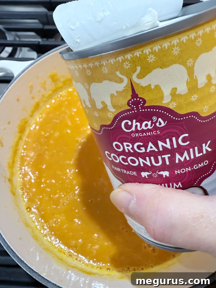 Adding coconut milk to the soup pot.