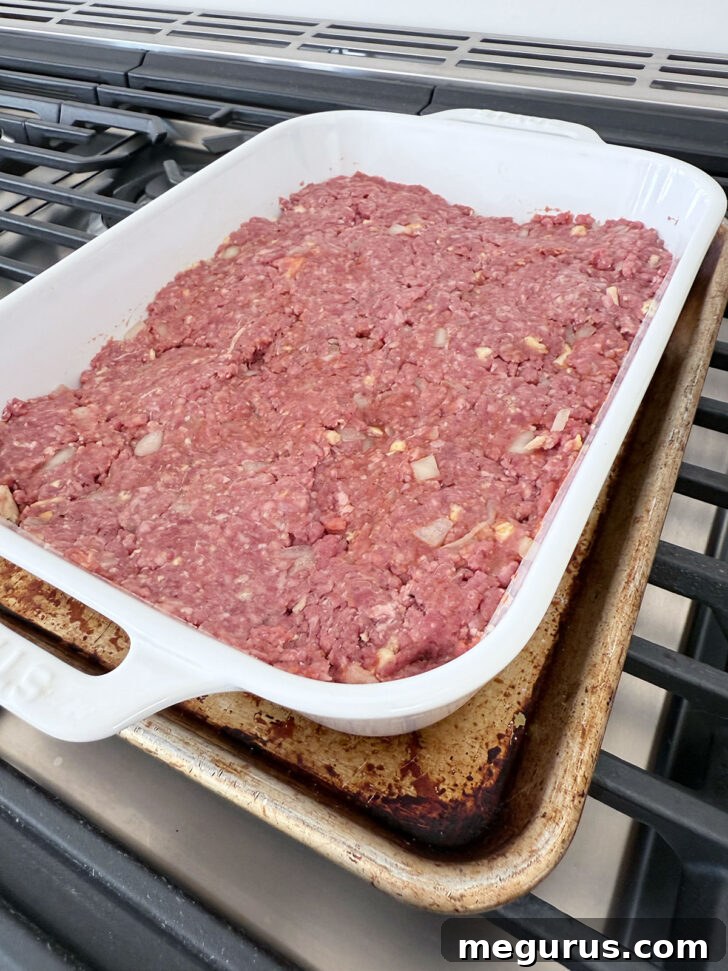 Partially baked meatloaf mixture in the casserole dish, ready for sauce.