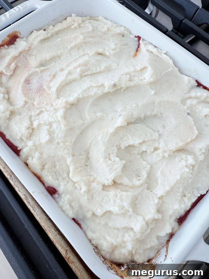 Mashed potatoes evenly spread over the sauced meatloaf casserole.
