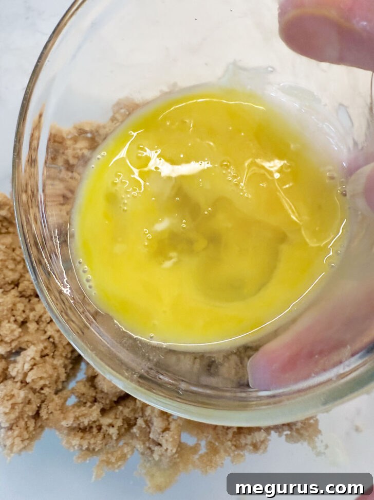 Beaten egg being added to the butter and brown sugar mixture.