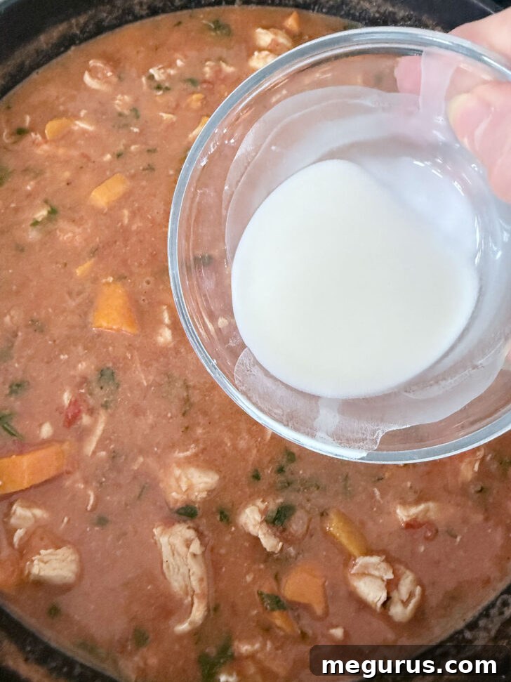 Thickening the African chicken stew with a cornstarch slurry.