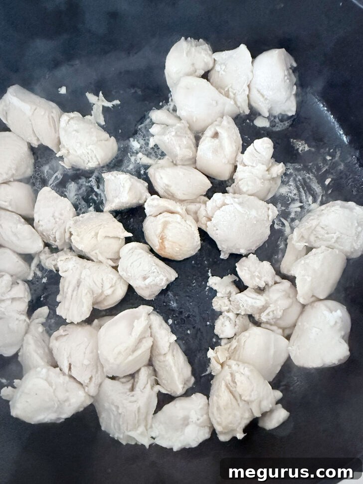 Chicken pieces cooking in a skillet.