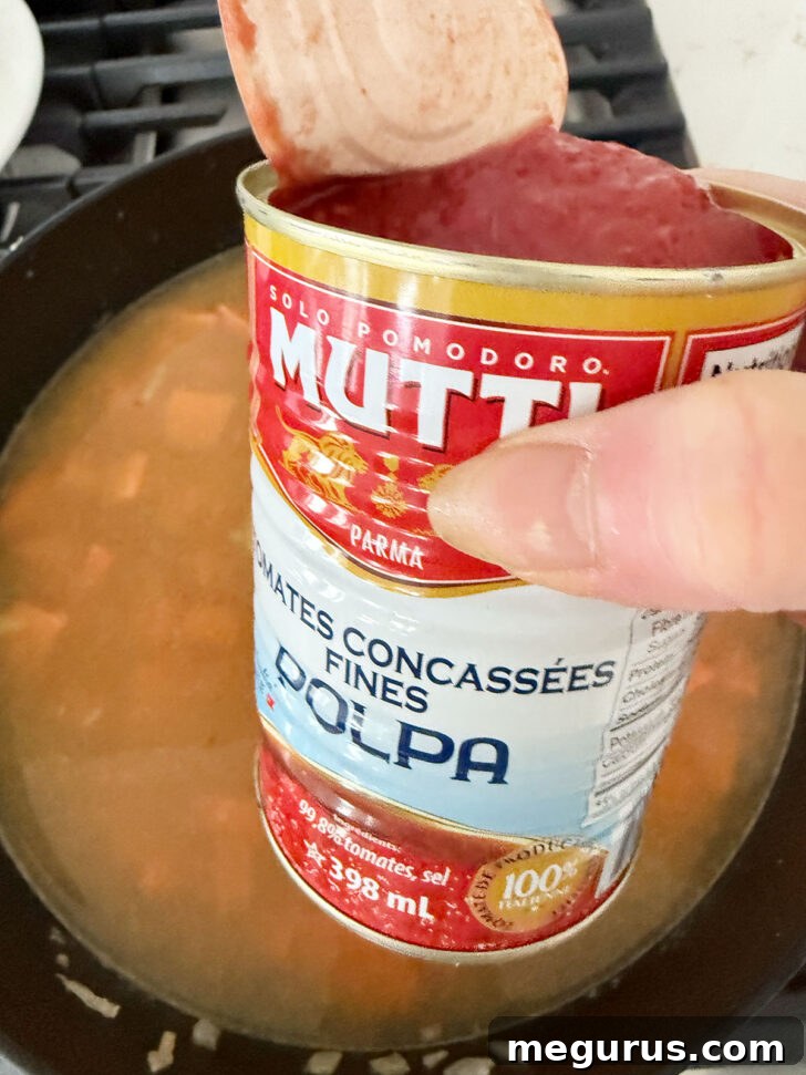 Adding the chopped tomatoes to the skillet.