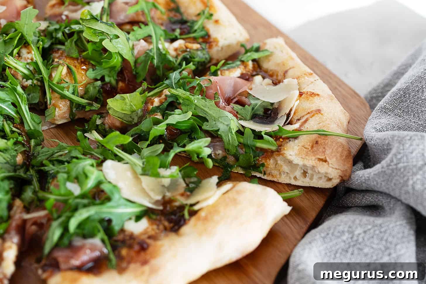 Fig and pig pizza on a pizza peel sliced. A close-up view showing the vibrant toppings and crispy crust.