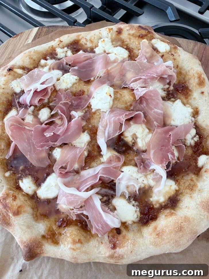Prosciutto added to the baked pizza, showing the next layer of topping.