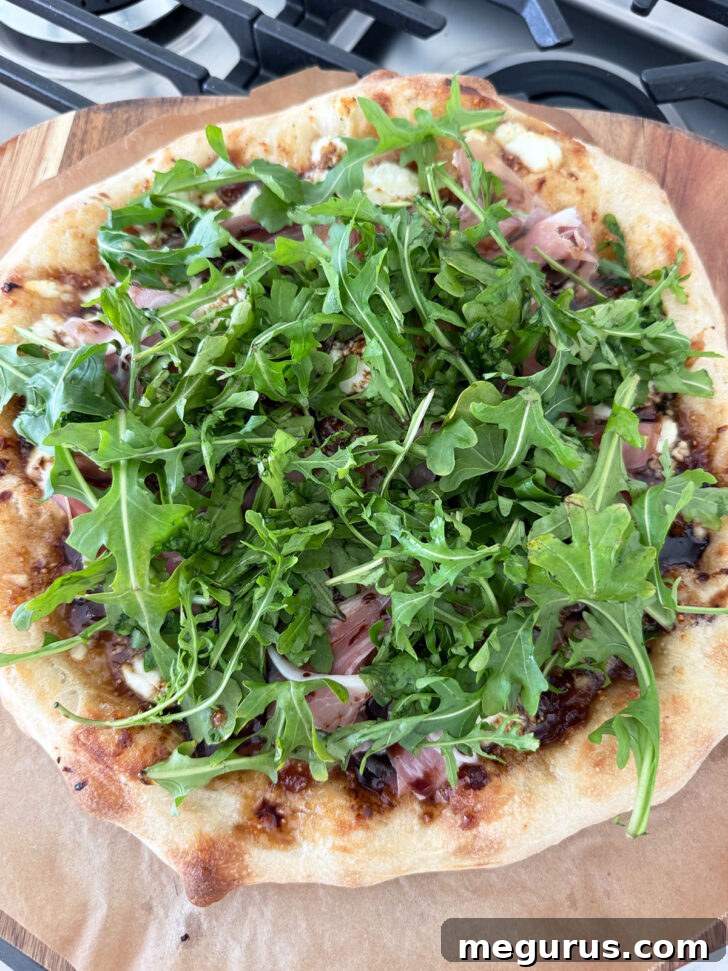 Finished Fig and Pig pizza, topped with fresh arugula and Parmesan shavings.