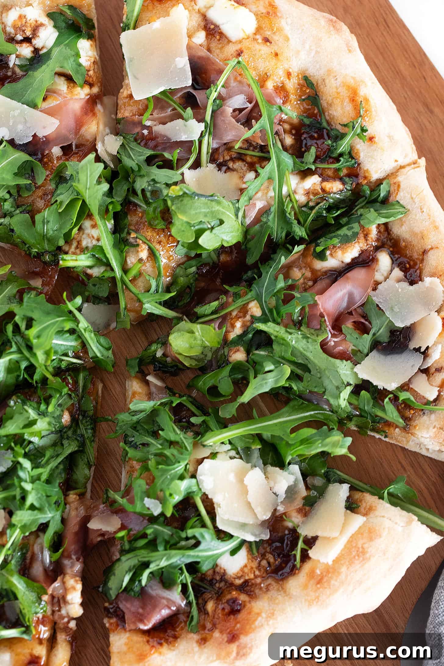 Fig and pig pizza sliced on a pizza peel, showcasing the layers of toppings.