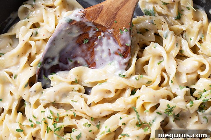 Cafeteria noodles in the skillet with a wooden spoon.