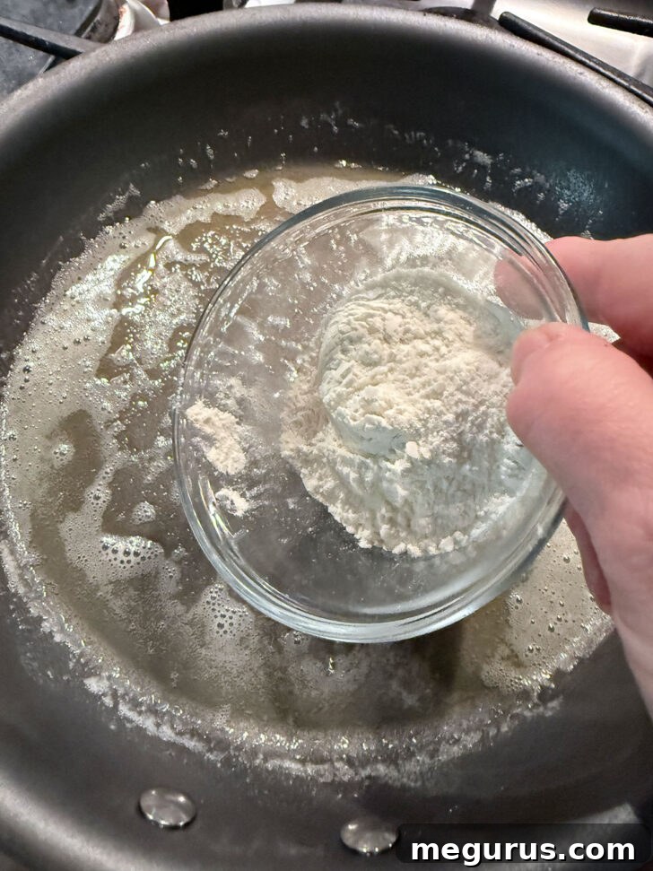 Adding flour to melted butter in a skillet.