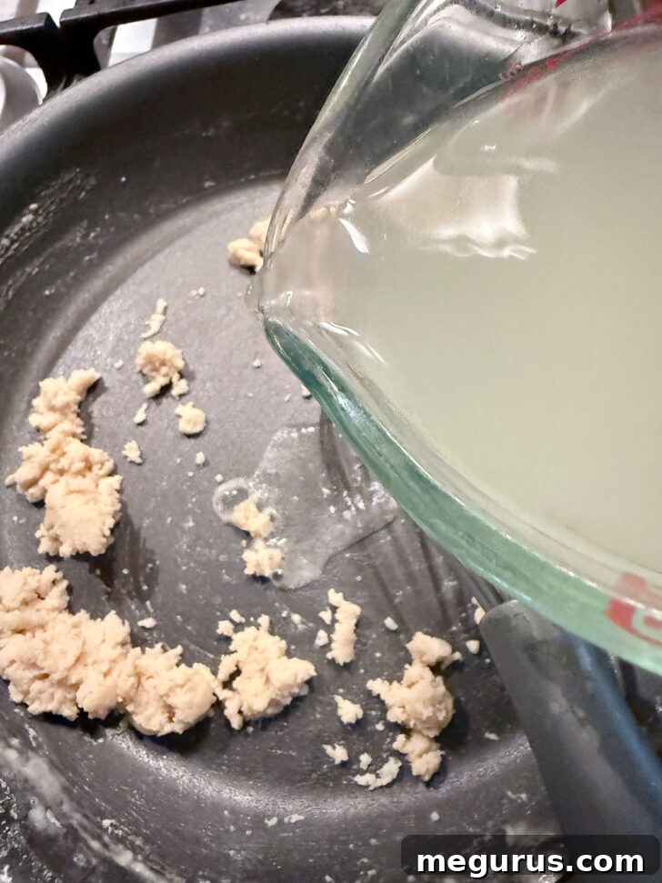 Adding chicken broth to the skillet with the flour and butter.