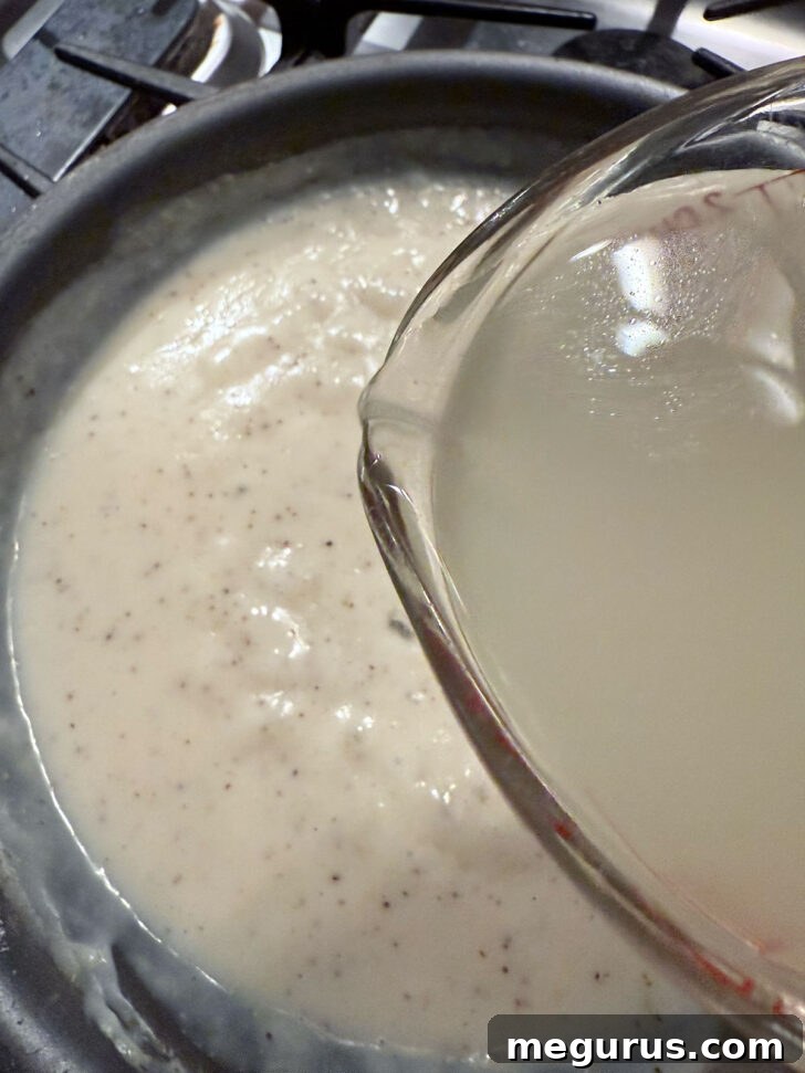 Adding more chicken broth to the skillet.