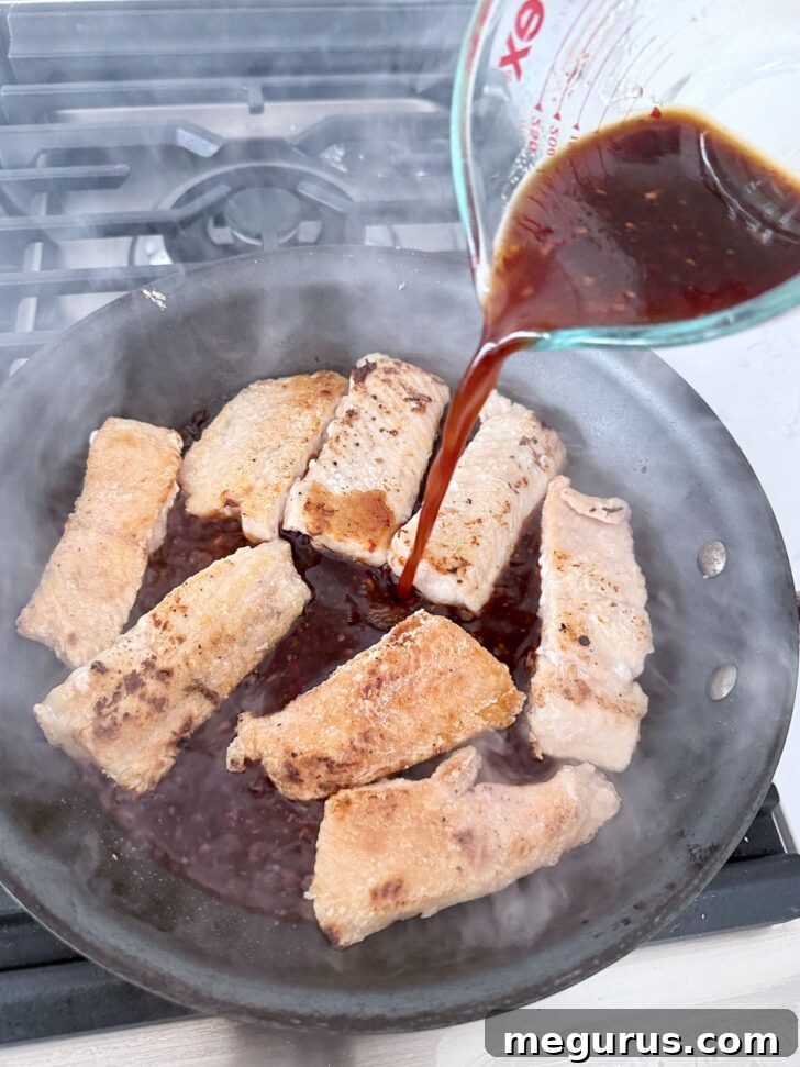 Adding the sauce to the crispy salmon.