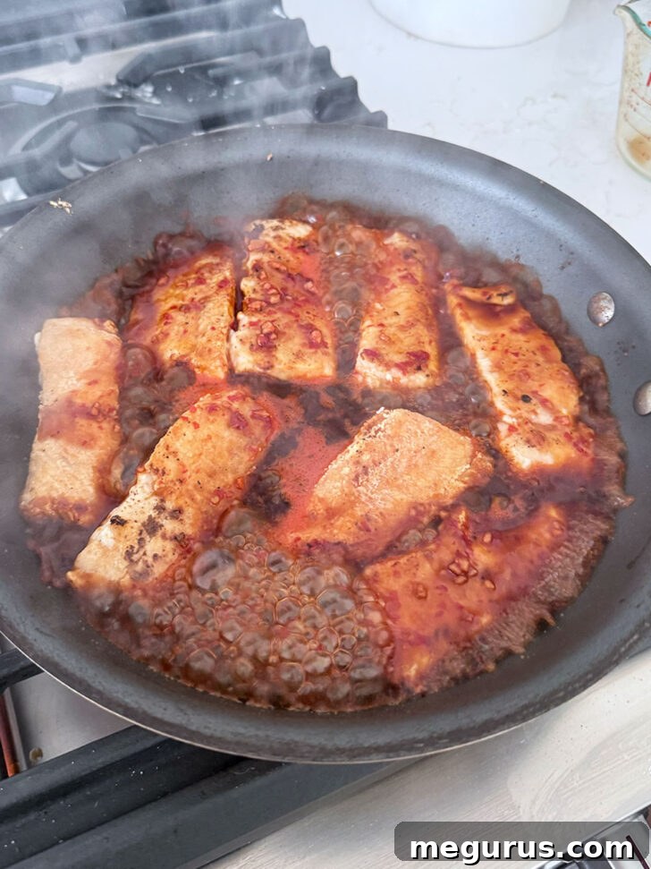 Sauce simmering with the salmon to thicken.