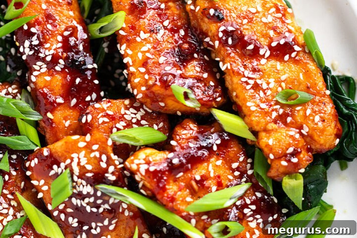Sticky spicy salmon on a serving platter with cooked spinach.