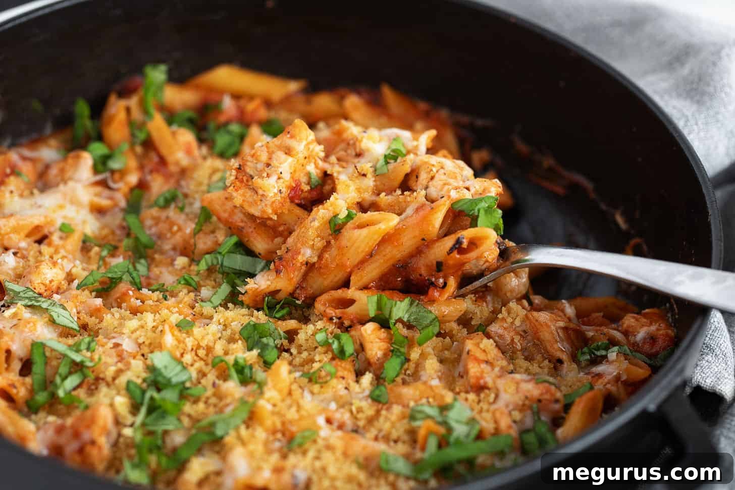 Chicken parmesan pasta in a skillet with a spoon, ready to be served.